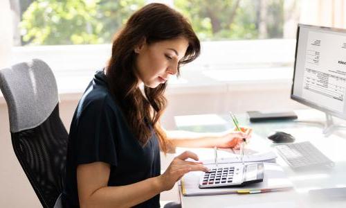 Accountant with a bachelor's degree seated at desk calculating balances 