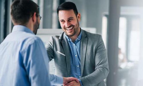 Business professional smiling and shaking hands with coworker