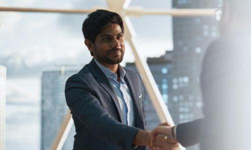 MBA business analytics graduate shaking hands with coworker